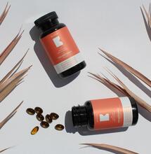 CBD softgel capsules against a white background decorated with palm leaves.