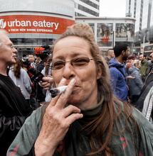 an old lady smoking a big fatty joint in the middle of a crowd. 