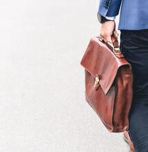 man holding a brown leather bag. 