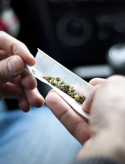 Persona liando un porro de marihuana en el interior de un coche aparcado