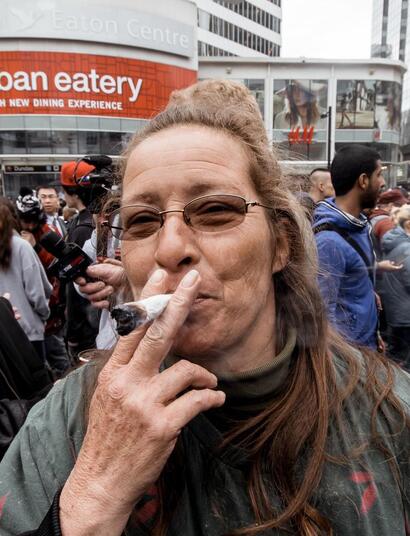 an old lady smoking a big fatty joint in the middle of a crowd. 