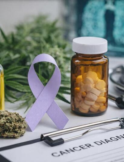Image showing a bottle of cannabis oil alongside cancer awareness symbols, including a ribbon and medical items such as a stethoscope and prescription container, representing the intersection of cannabis, cancer care, and health research.
