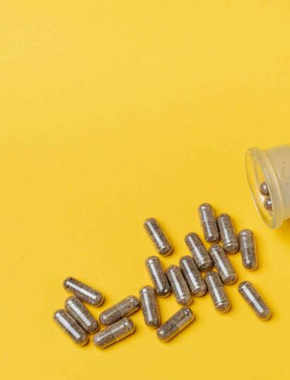 THC CBD capsules against a yellow background.