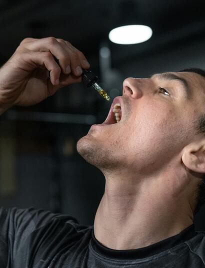 Hombre aplicando aceite de CBD con un gotero, ilustrando el consumo sublingual para una absorción eficiente y evitar el metabolismo hepático