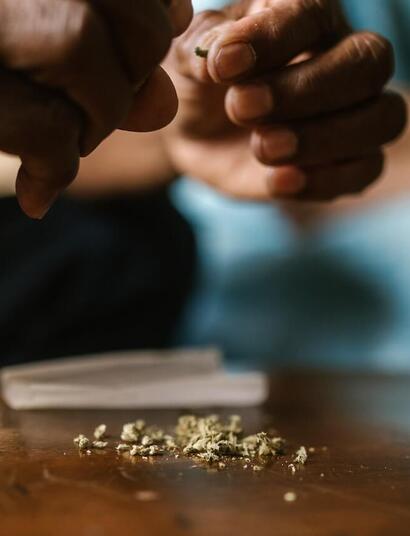 a person holding marijuana and preparing a joint.