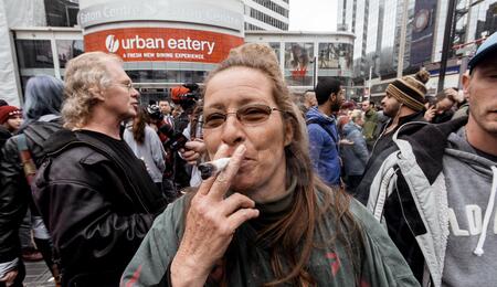 an old lady smoking a big fatty joint in the middle of a crowd. 