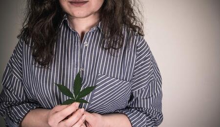 woman holding leaf of marijuana. 