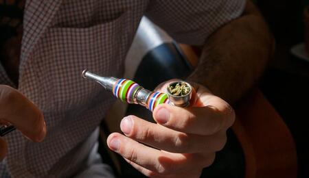 a man holding a pipe filled with cannabis, a known remedy in the treatment of eating disorders