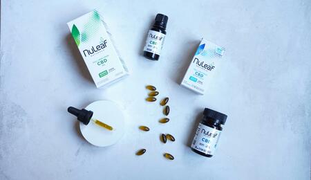 Composición profesional de productos de cannabidiol (CBD) en aceite y cápsulas sobre un fondo limpio. La imagen representa la estandarización y variedad de formatos de administración analizados en el meta-análisis de Lattanzi sobre la epilepsia.