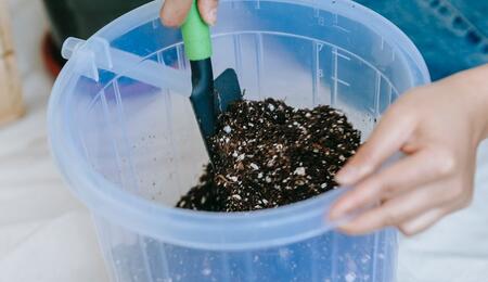 mixing soil and fertiliser in a bucket