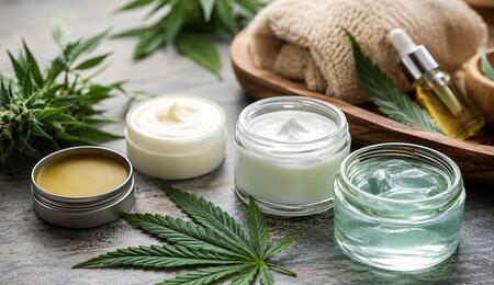 Cannabis topical products including balms, creams, and cooling gels displayed beside cannabis leaves in a spa-style wellness setting.