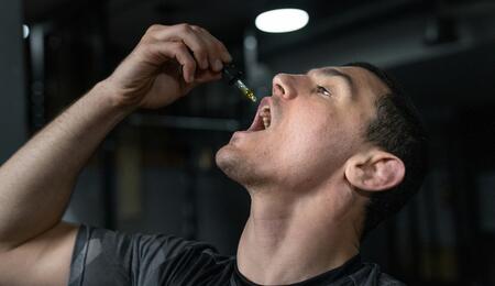 Hombre aplicando aceite de CBD con un gotero, ilustrando el consumo sublingual para una absorción eficiente y evitar el metabolismo hepático