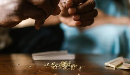 a person holding marijuana and preparing a joint.