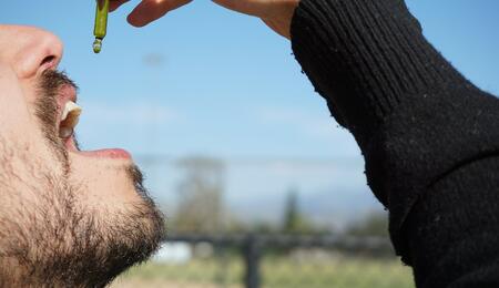 a man is taking a drop of CBD oil, which is available as full-spectrum, broad-spectrum and isolate form