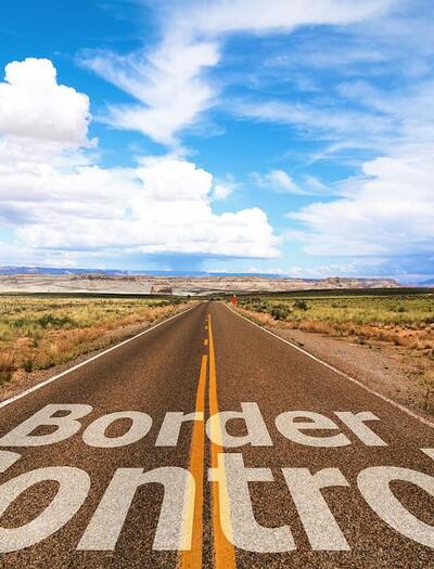 "Border Control" letter sign on a highway passing through a field in what feels like typical New Mexico landscape. 