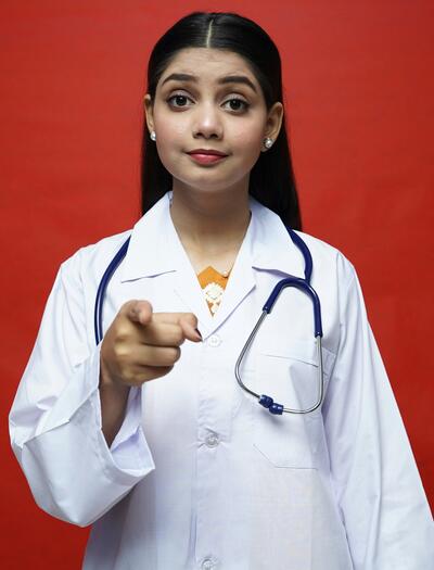 Doctora apuntando con el dedo en señal de prejuicio hacia un paciente, ilustrando el concepto de Stinkma o estigma por olor a cannabis en la consulta médica.