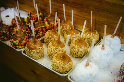 Trays of homemade cannabis-infused salted caramel apples topped with nuts, chocolate, and candy for a Halloween weed edible spread.
