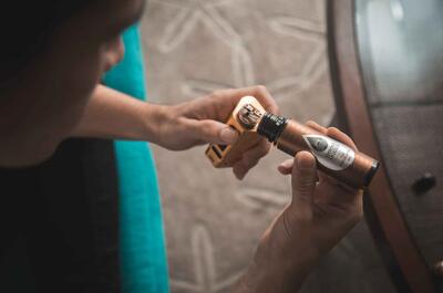 Person refilling a vape device with liquid from a small bottle, illustrating cannabis consumption methods and workplace cannabis policy considerations.