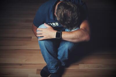 a man suffering from depression, sitting on the floor.