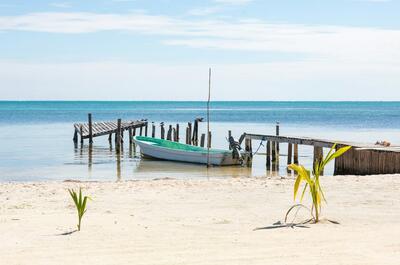 idyllic scenery at Caye Caulker island in Belize showing the coastline with the perfect blue sea and a fishermen boat on the beach.