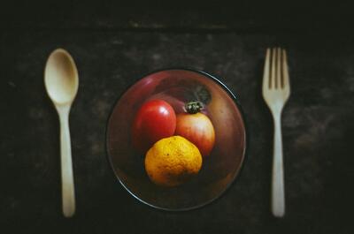 an image of a bowl with fruits against a dark background, with a spoon and a fork left and right to the bowl.
